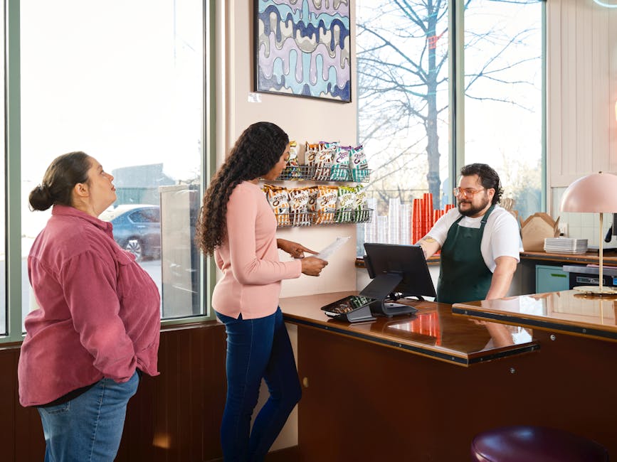 Two customers interacting with staff at a restaurant point of sale counter.