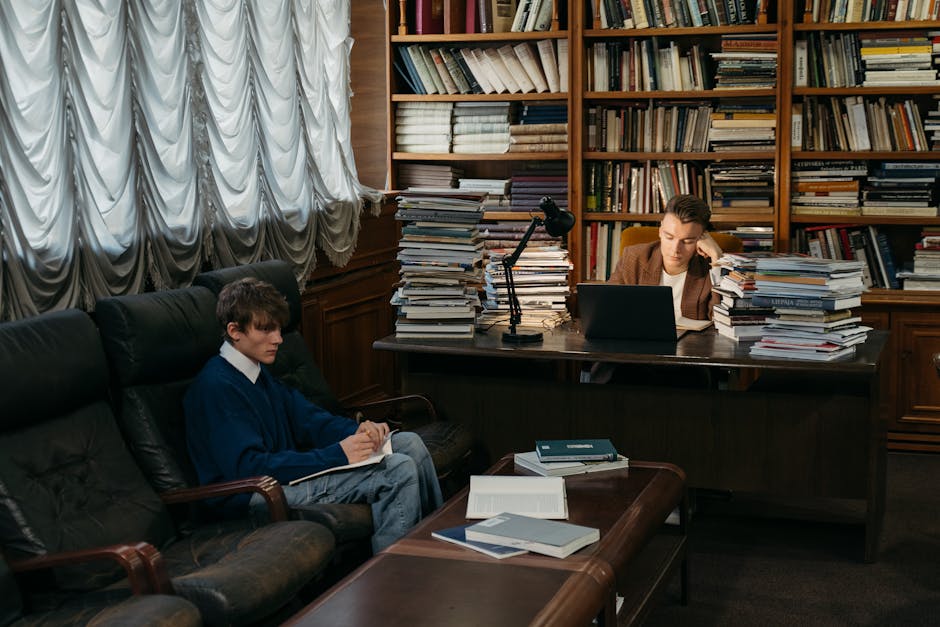 Two college students studying in a cozy library with books and laptop, reflecting academic life.