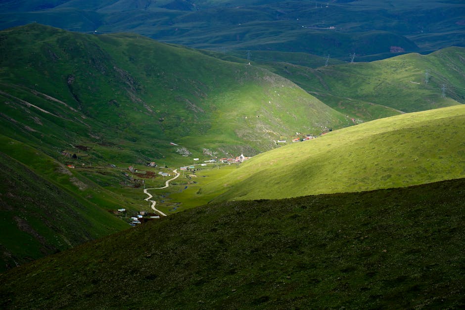 Captivating view of a lush green valley with sunlight and shadows creating a serene landscape.