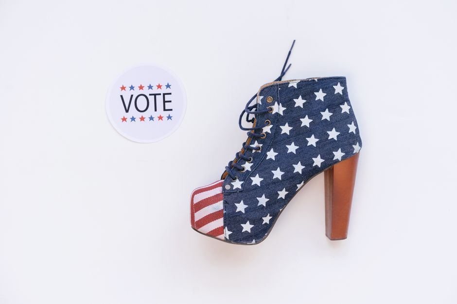 High heel with American flag design beside a voting sticker on white background.