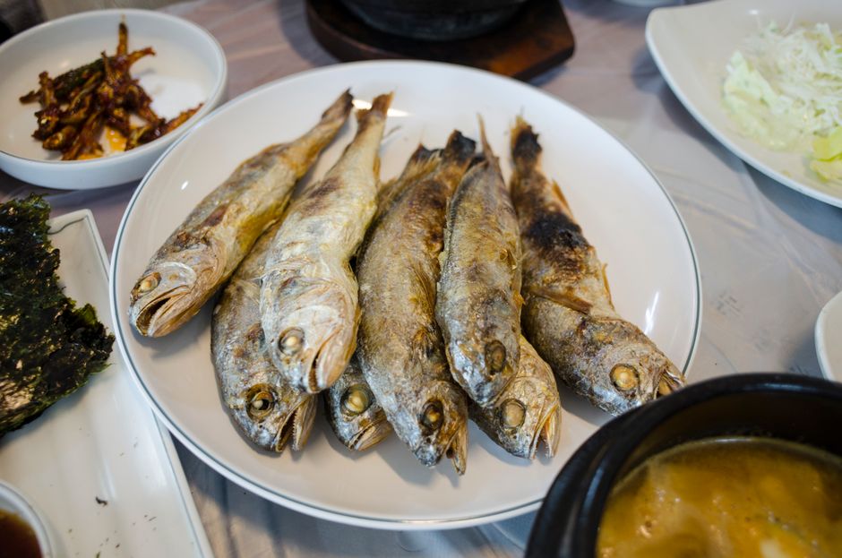 Close-up of grilled fish served in a traditional Korean meal setting, highlighting culinary delight.