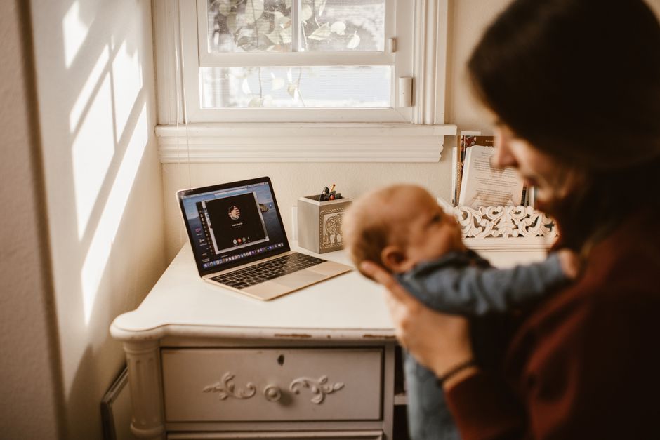 A mother holding her baby while on a video call indoors, showcasing modern connectivity and family love.