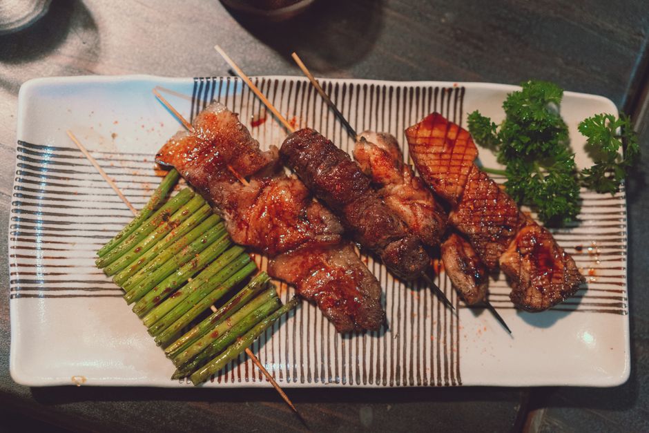 Delicious grilled skewers served with asparagus and herbs on a stylish plate.