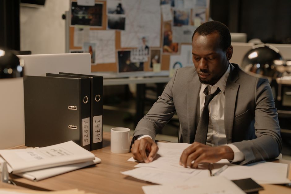Man in business suit working late at office desk with documents and files.
