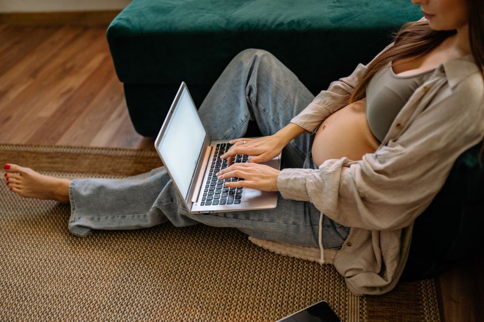 Expectant mother working remotely at home with her laptop, showcasing modern maternity lifestyle.