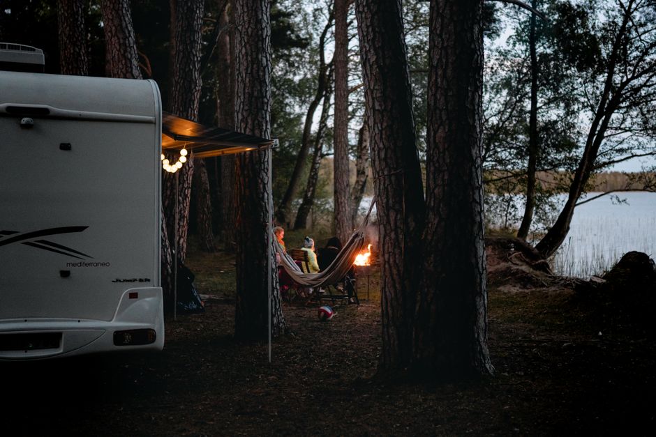 Cozy campsite with a camper van by a serene lake in Lithuania's forest. Ideal outdoor getaway.