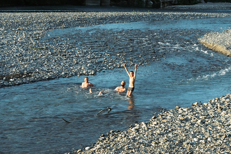 Three people enjoying a swim in a refreshing river in Gagra, surrounded by pebble banks.