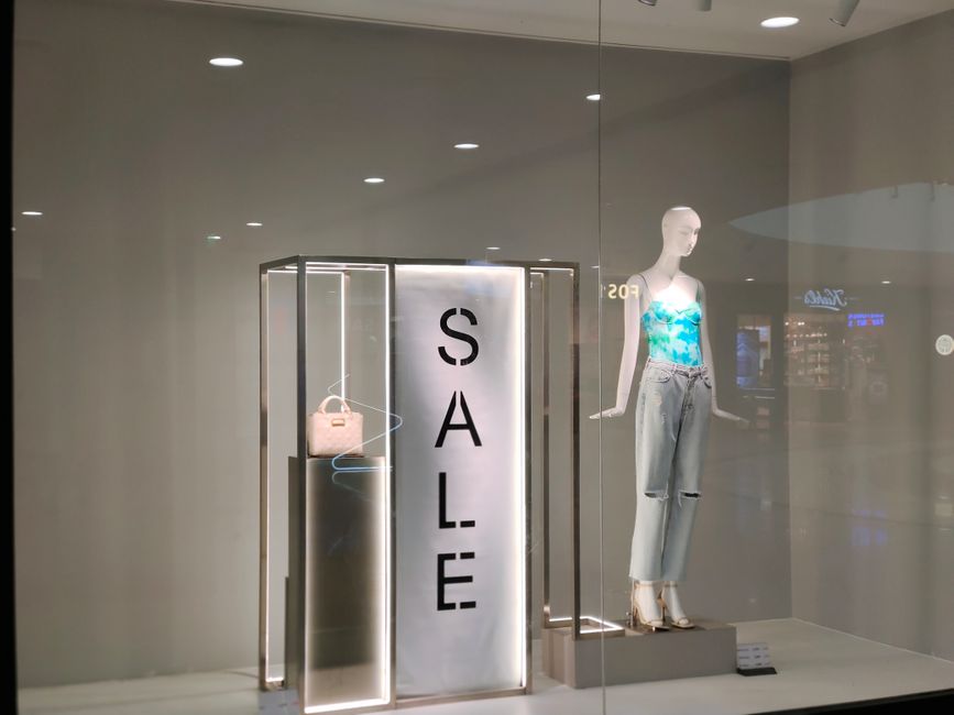 Stylish window display featuring sale sign and fashionable mannequin in trendy outfit.