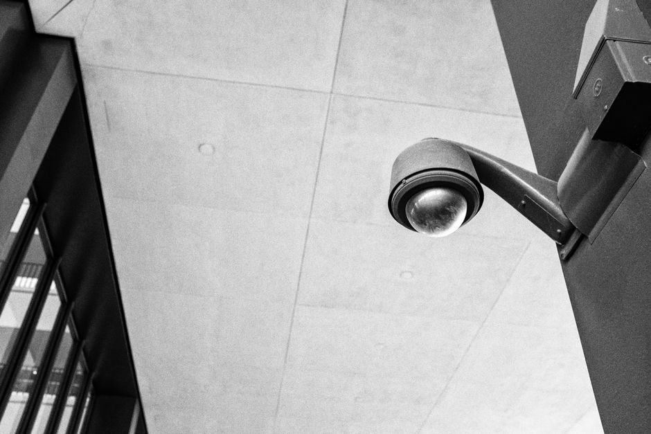 Monochrome image of a modern surveillance camera mounted outdoors, emphasizing security.