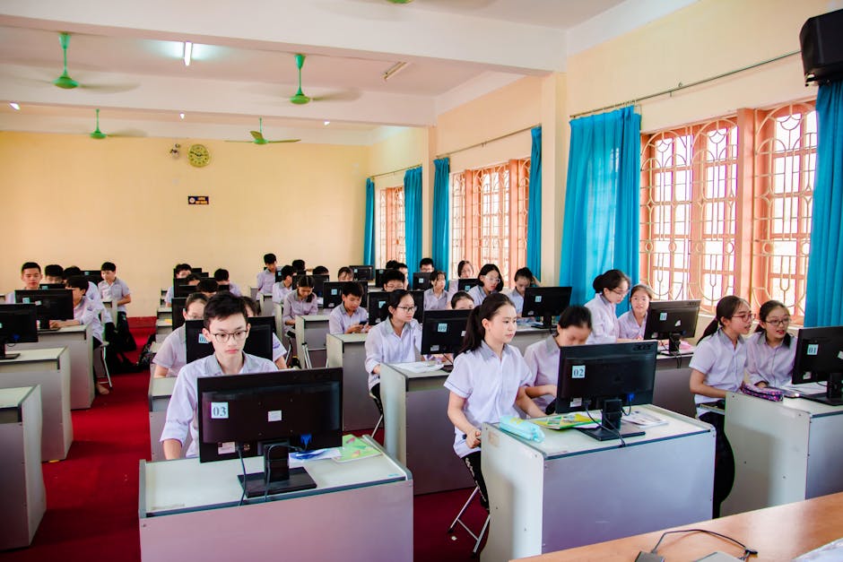 Asian students in uniform learning in a computer lab, focused on their tasks.