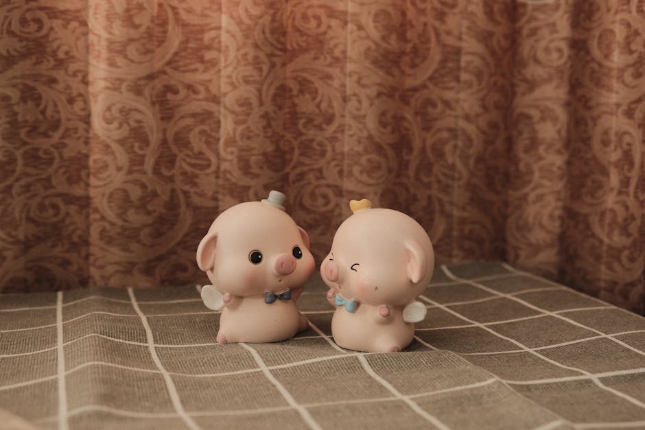 Cute pig-shaped figurines with wings on a patterned cloth background.