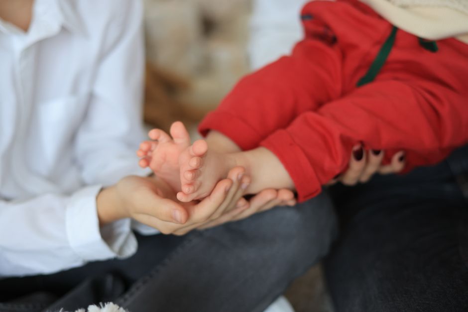Close-up of a baby’s feet gently held by parental hands, symbolizing love and care.