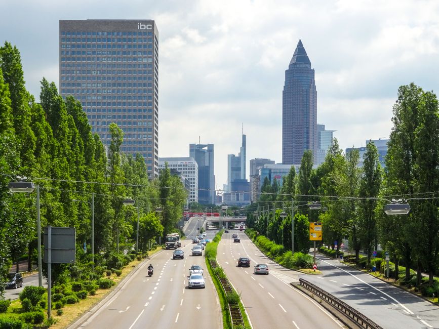 Panoramic view of Frankfurt's skyline with traffic and skyscrapers under a cloudy sky.