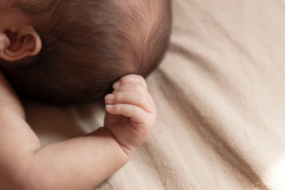 Intimate close-up of a baby's hand resting on soft fabric, capturing innocence and tranquility.