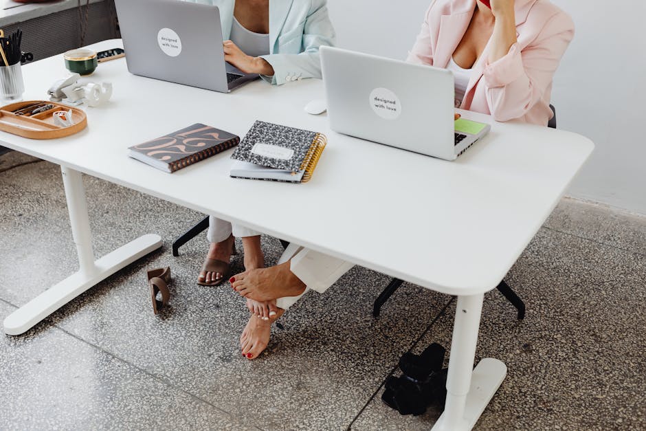 Two women collaborate in a modern office setting, showcasing teamwork and connection.