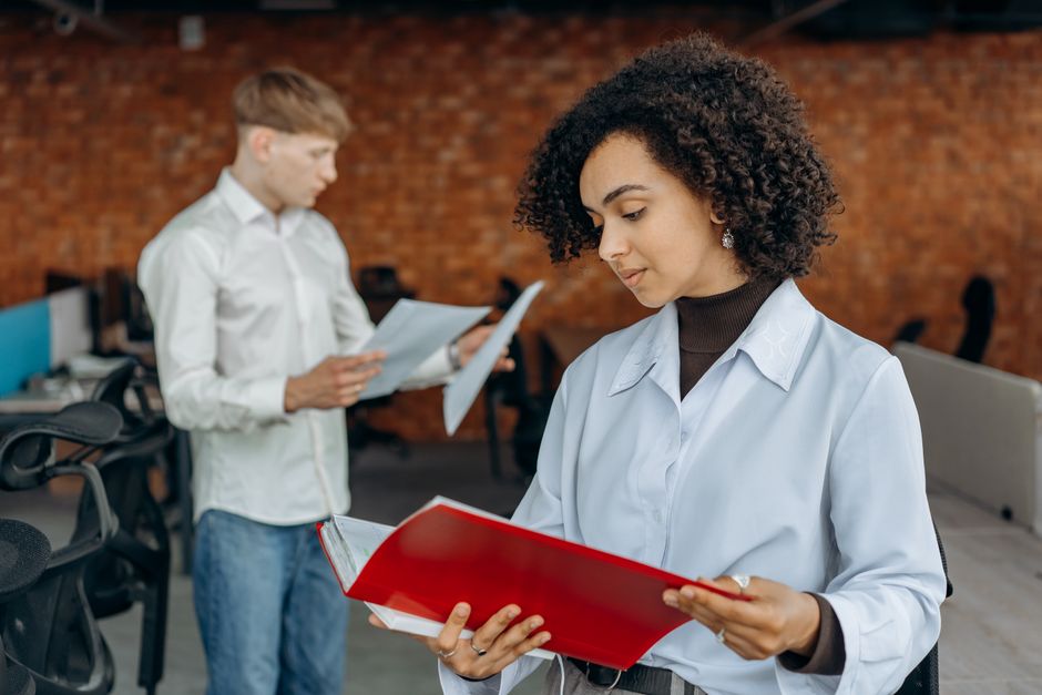 Two young professionals collaborate on finance reports in a contemporary office space.