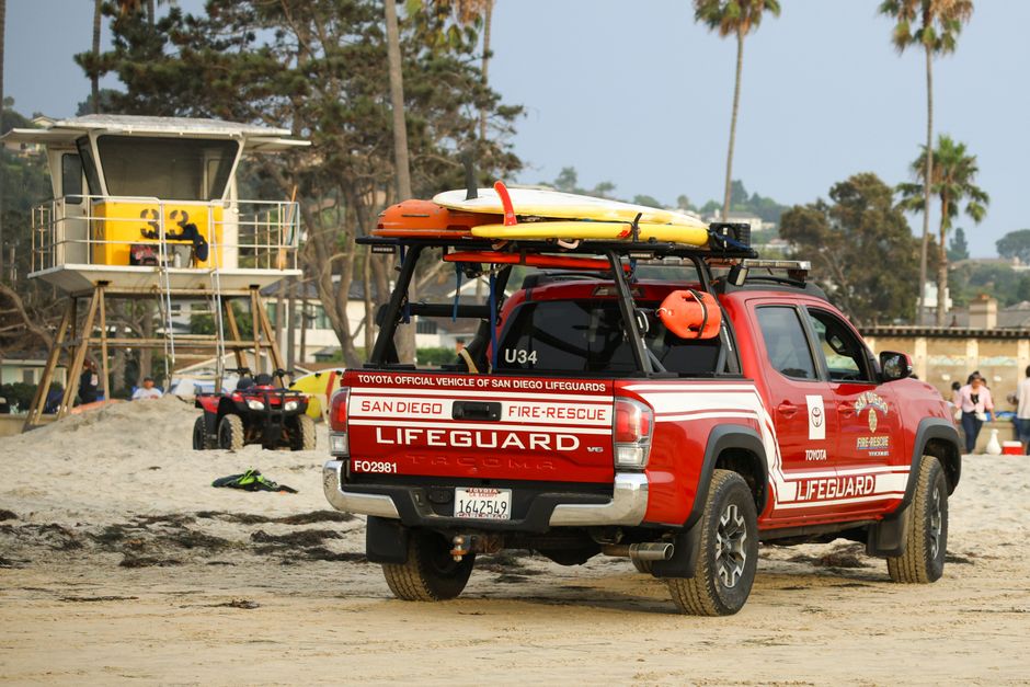 Lifeguard truck on a sandy beach near a lifeguard tower in San Diego.