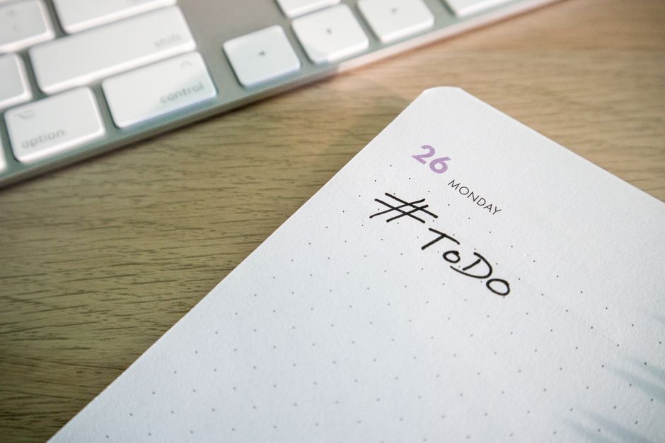 Close-up of a to-do list next to a computer keyboard on a desk.