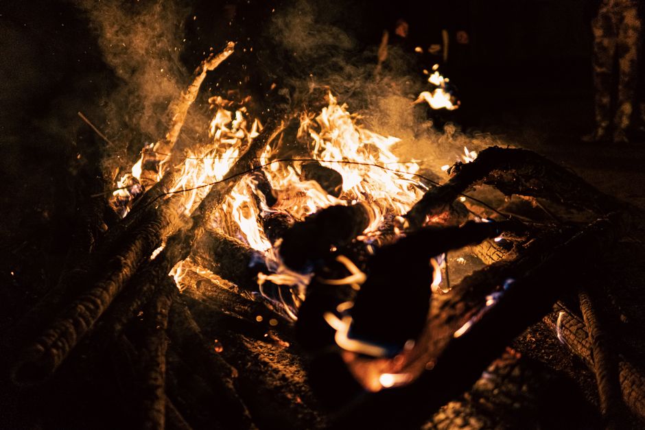 A vivid campfire with glowing flames and charred logs in the dark night atmosphere.