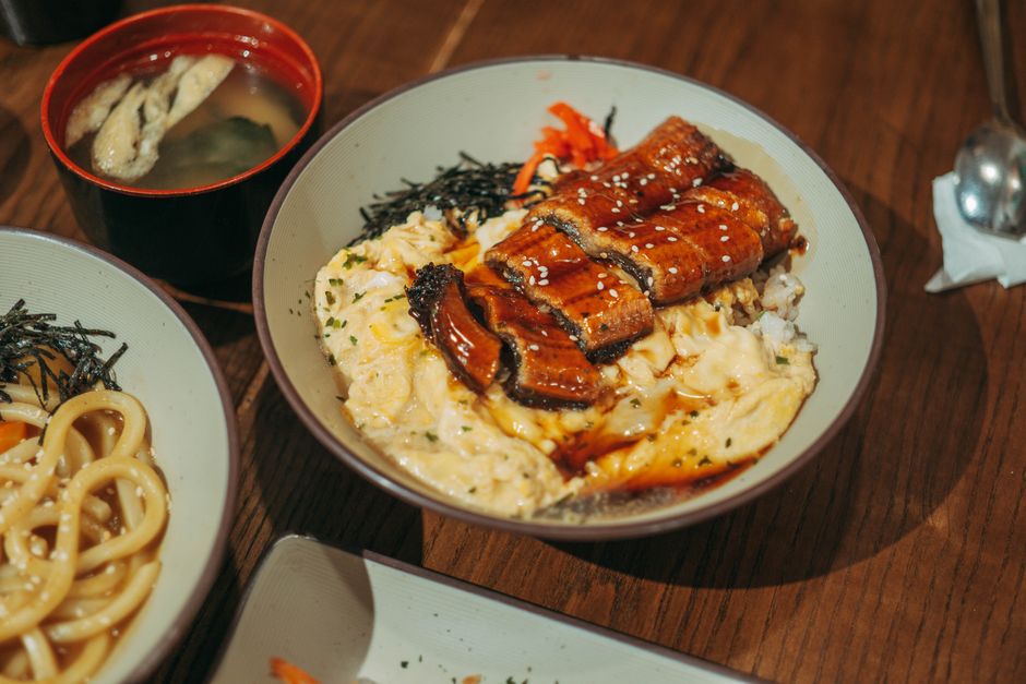 Mouthwatering unagi donburi served with udon and miso soup on a wooden table.