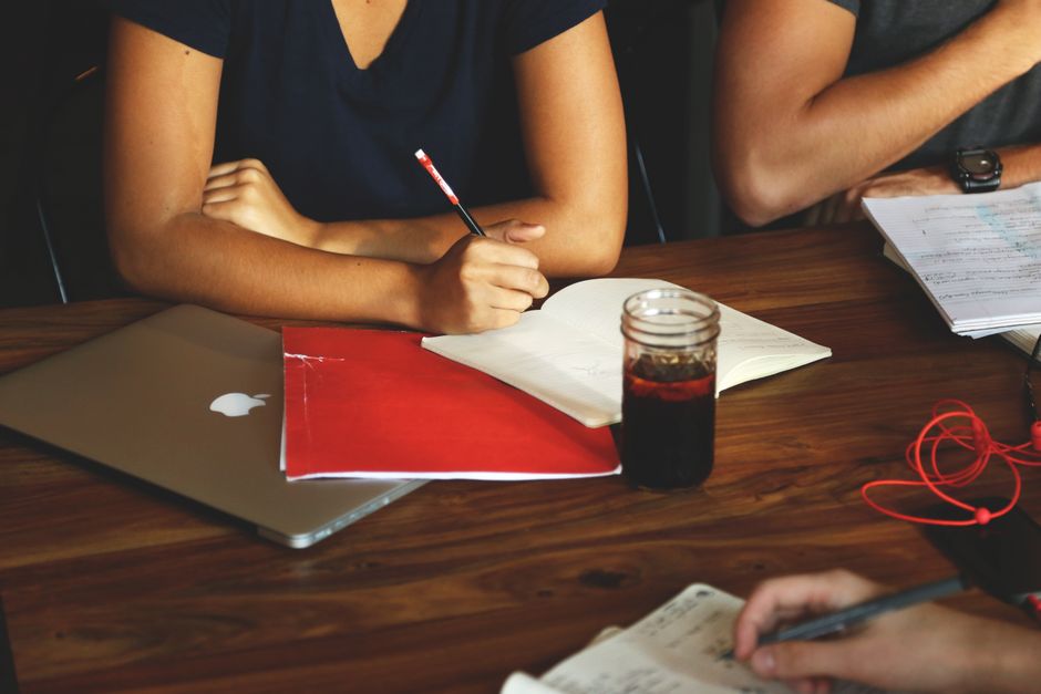 Group of adults collaborating in a modern workspace with laptops, notes, and refreshments.