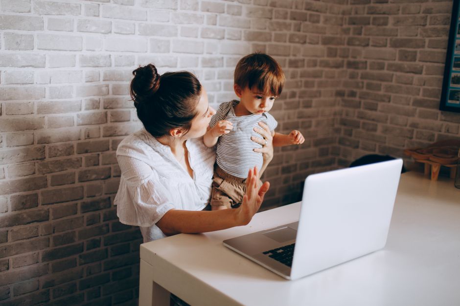 A mother and young child engaging with a computer in a cozy home setting.