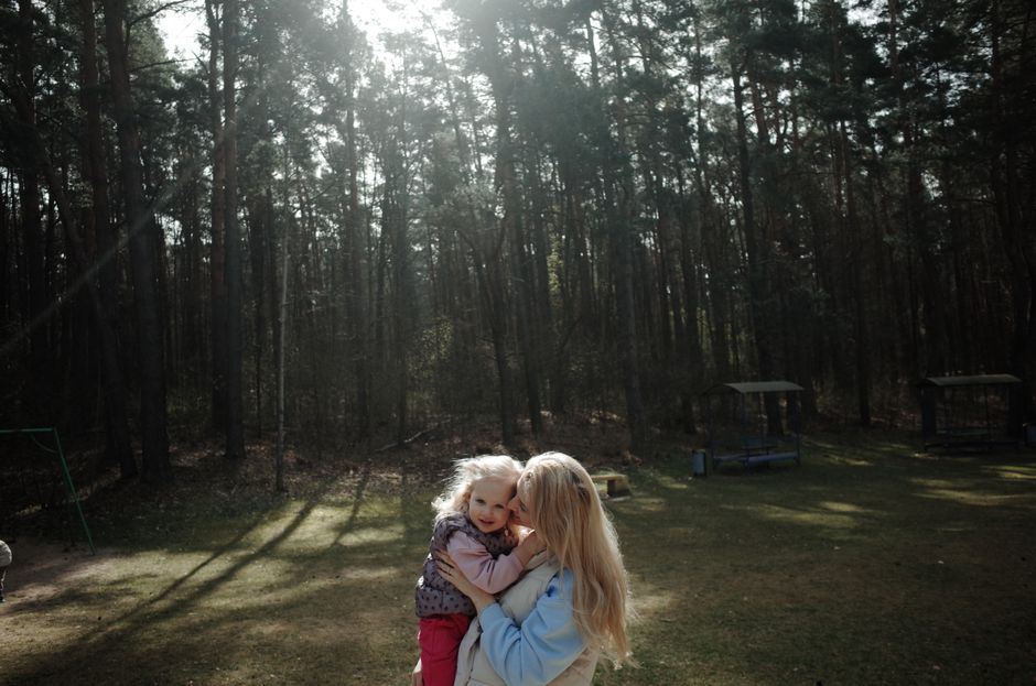 A warm embrace between a mother and daughter in a sunlit forest, capturing love and nature.