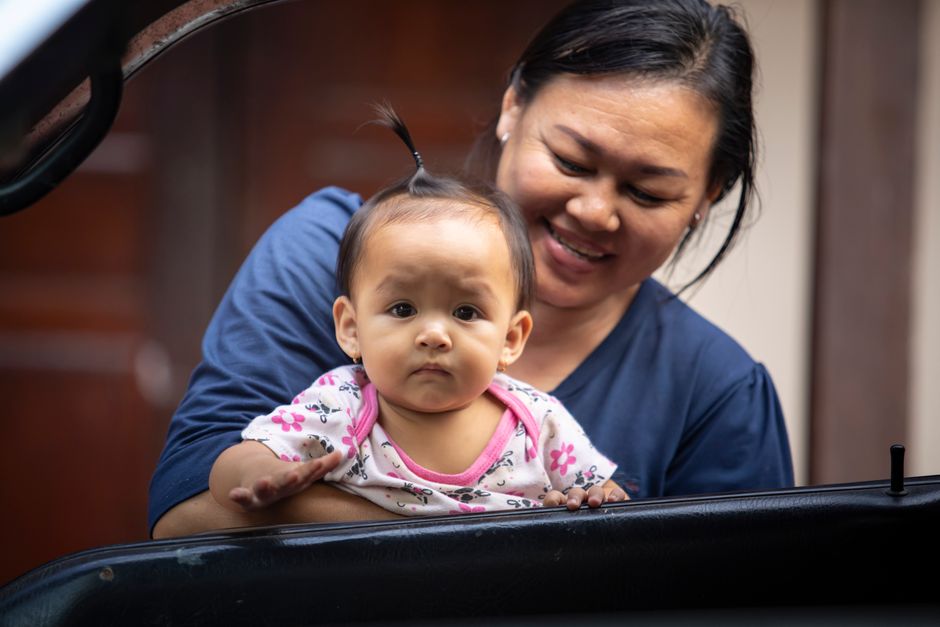 A mother joyfully holds her baby, showcasing a moment of family affection and happiness.