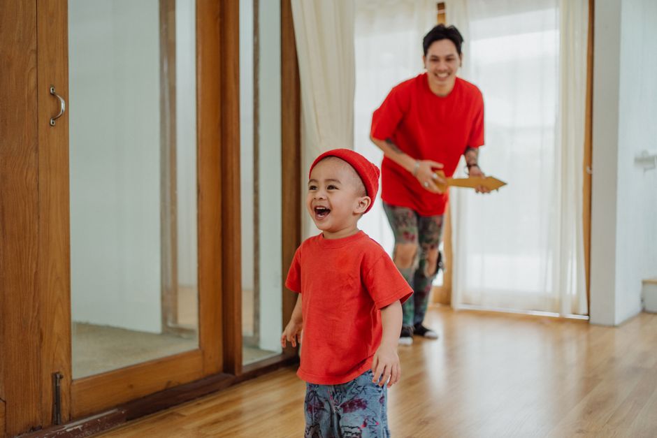 Father playing guitar toy with his son in a bright home setting.