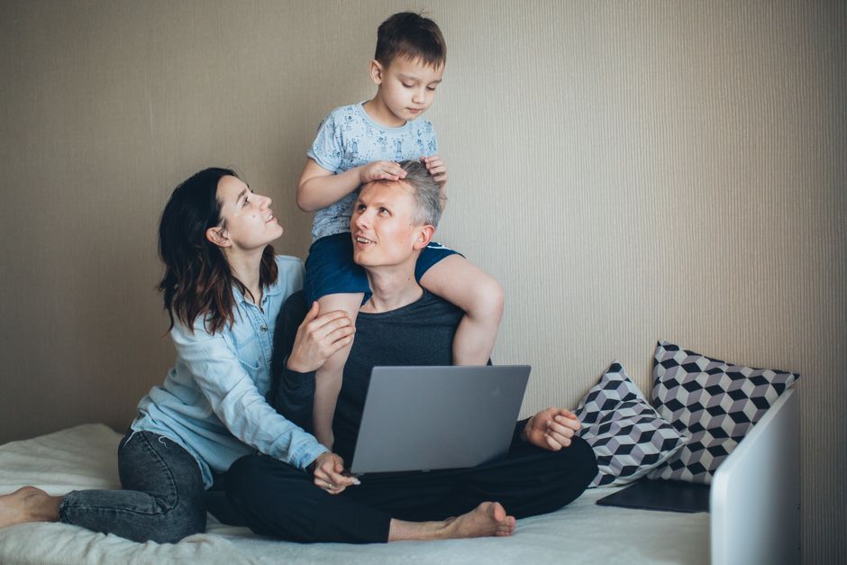 A joyful family moment indoors featuring a father, mother, and son bonding together with a laptop.