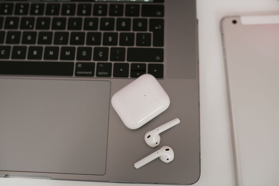 Close-up of a laptop, tablet, and wireless earbuds on a clean workspace.