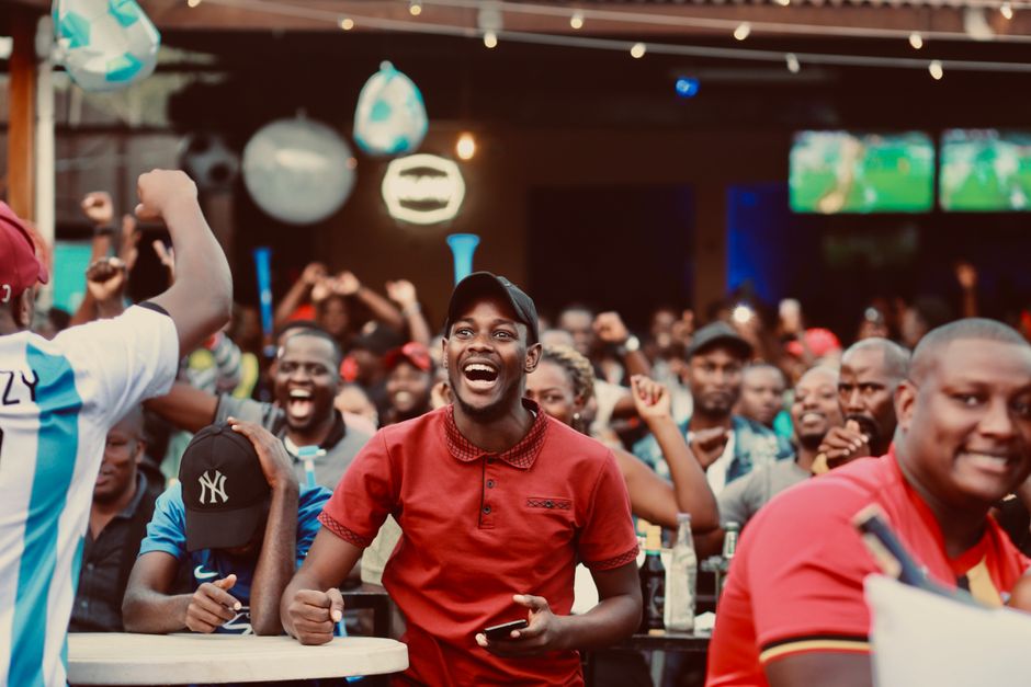 A lively group of fans enthusiastically cheering at a sports bar during a live match.