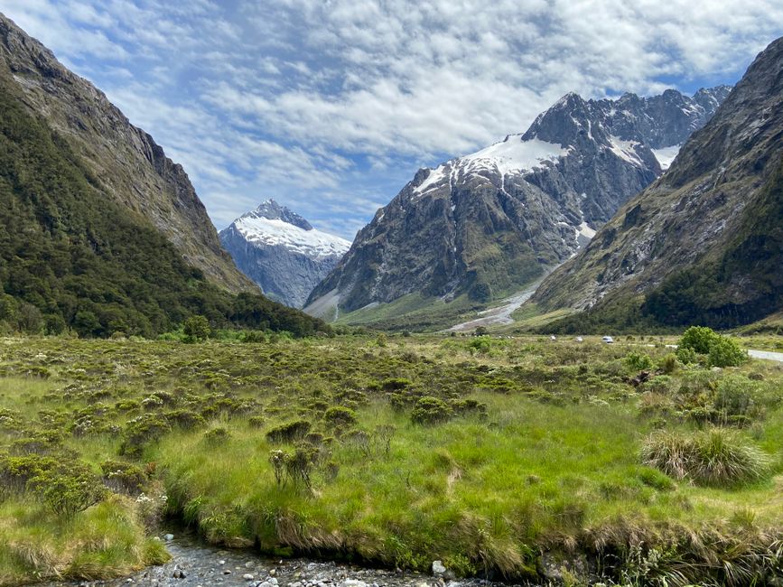 A breathtaking view of snowcapped mountains and a lush valley in New Zealand, showcasing natural beauty.