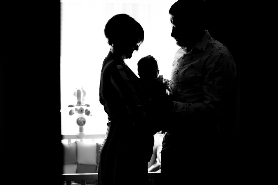 Heartwarming silhouette of parents holding their baby in a black and white setting.