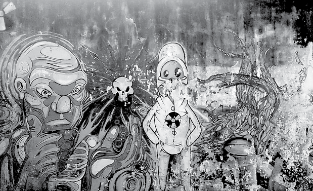 Grafiti mural en blanco y negro con una figura antropomorfa de rasgos monstruosos a la izquierda, una calavera al centro y una figura con traje protector y símbolo de radiactividad a la derecha, junto a formas orgánicas entrelazadas