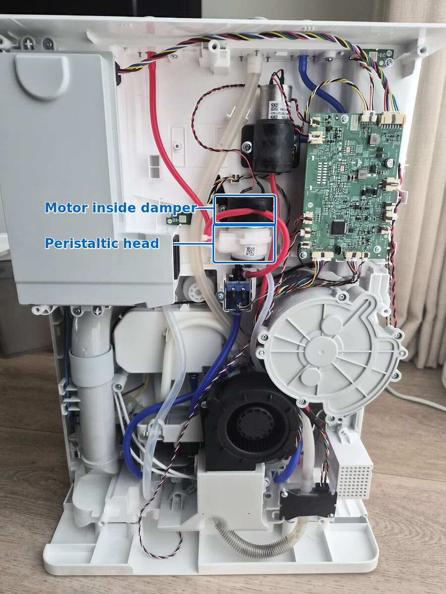 Open Roborock dock with the central pump assembly highlighted and its motor and white peristaltic head labeled.