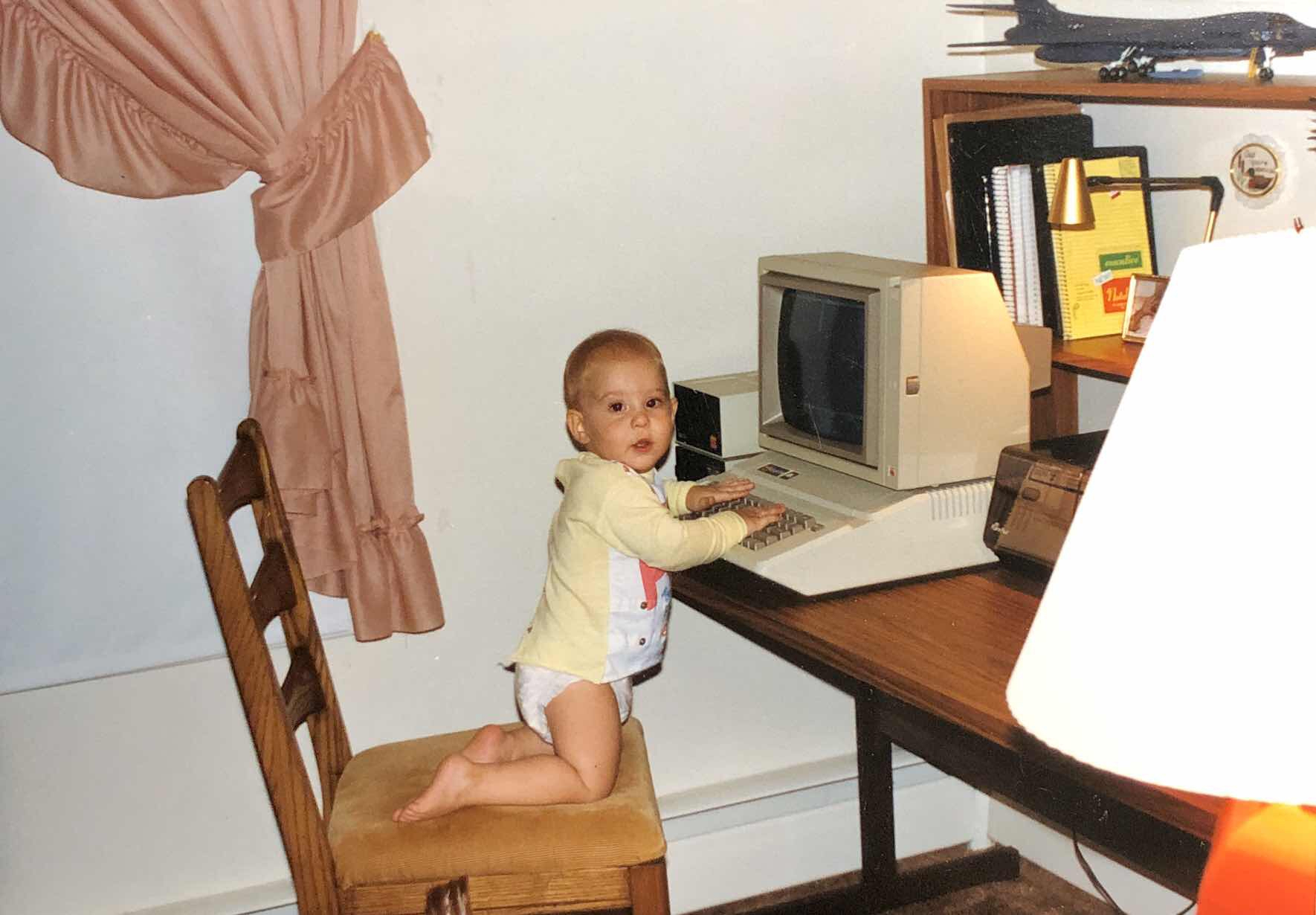 A picture of Brett as a diapered-toddler typing on an Apple IIe