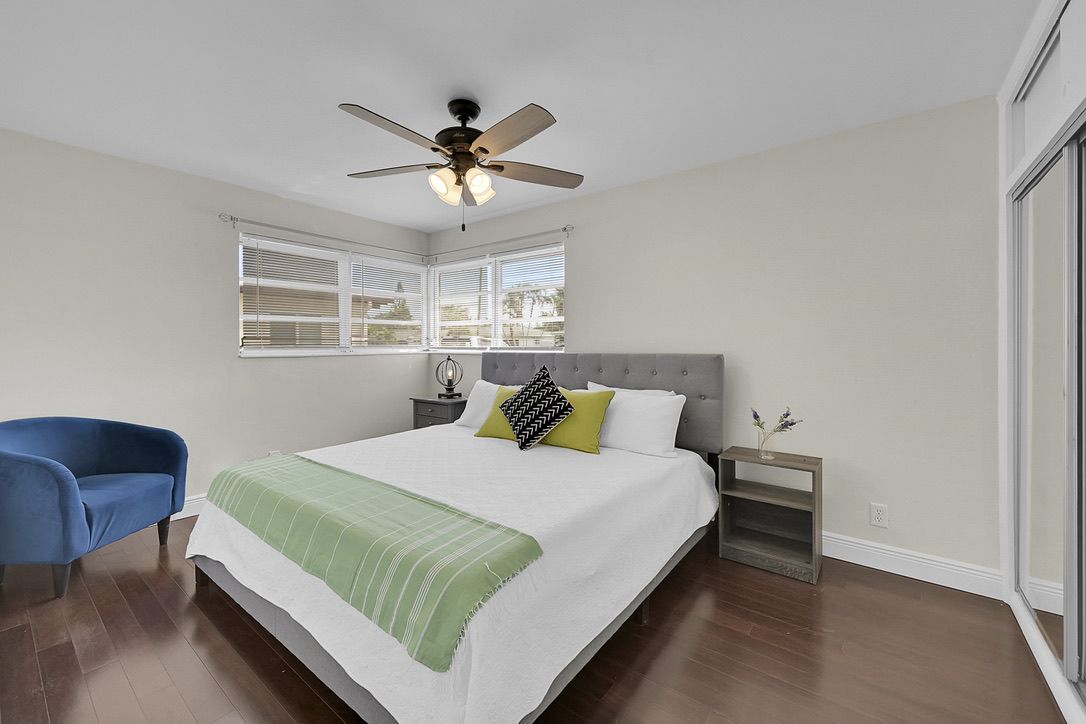 Primary bedroom with grey bed and blue accent chair