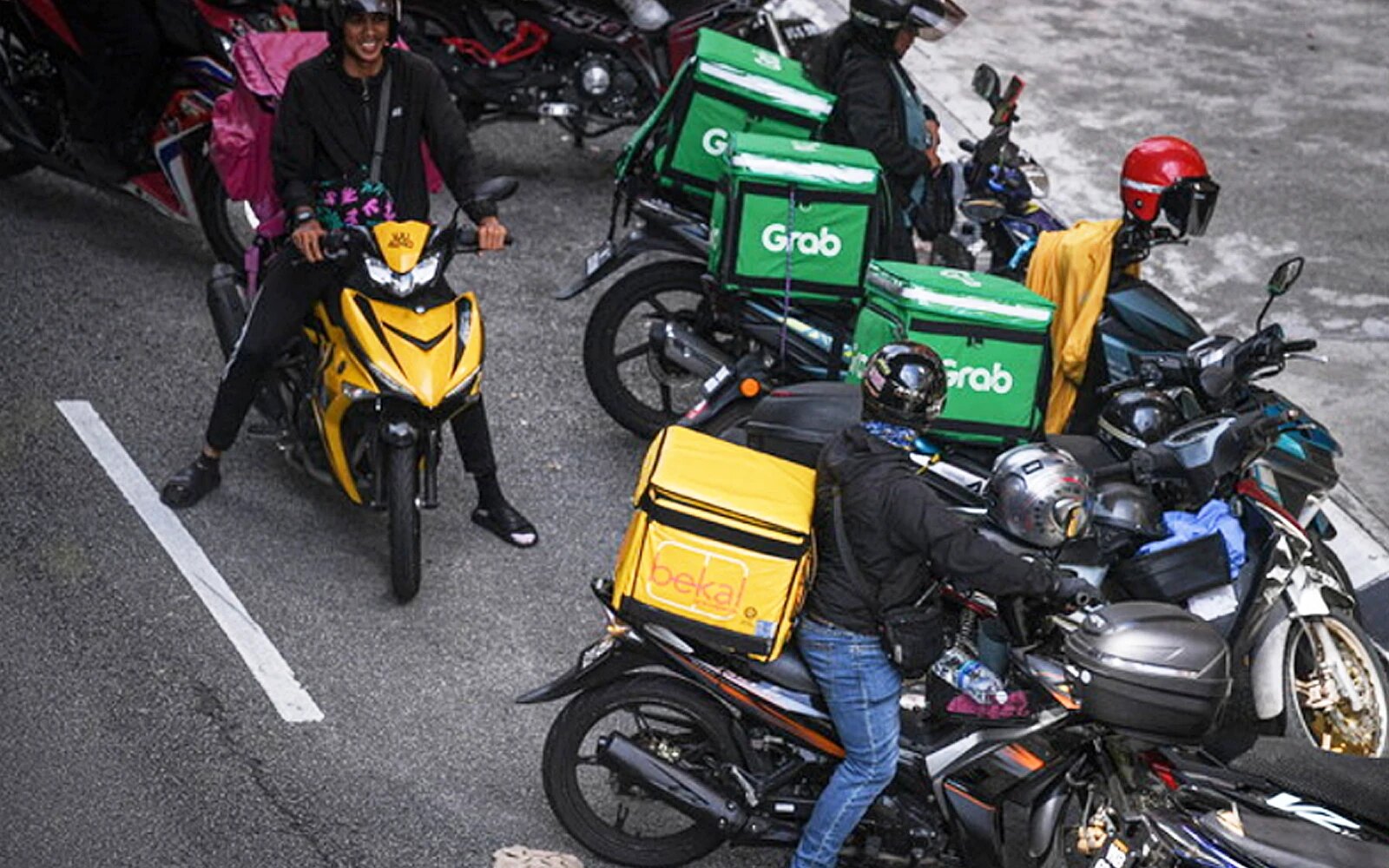 P-hailing riders and their insulated boxes. Malaysia gave parcel delivery by app its own legal class, counted 600,000 e-hailing and p-hailing drivers, and will set their minimum income in early 2027 — co-funded by the dominant platform.