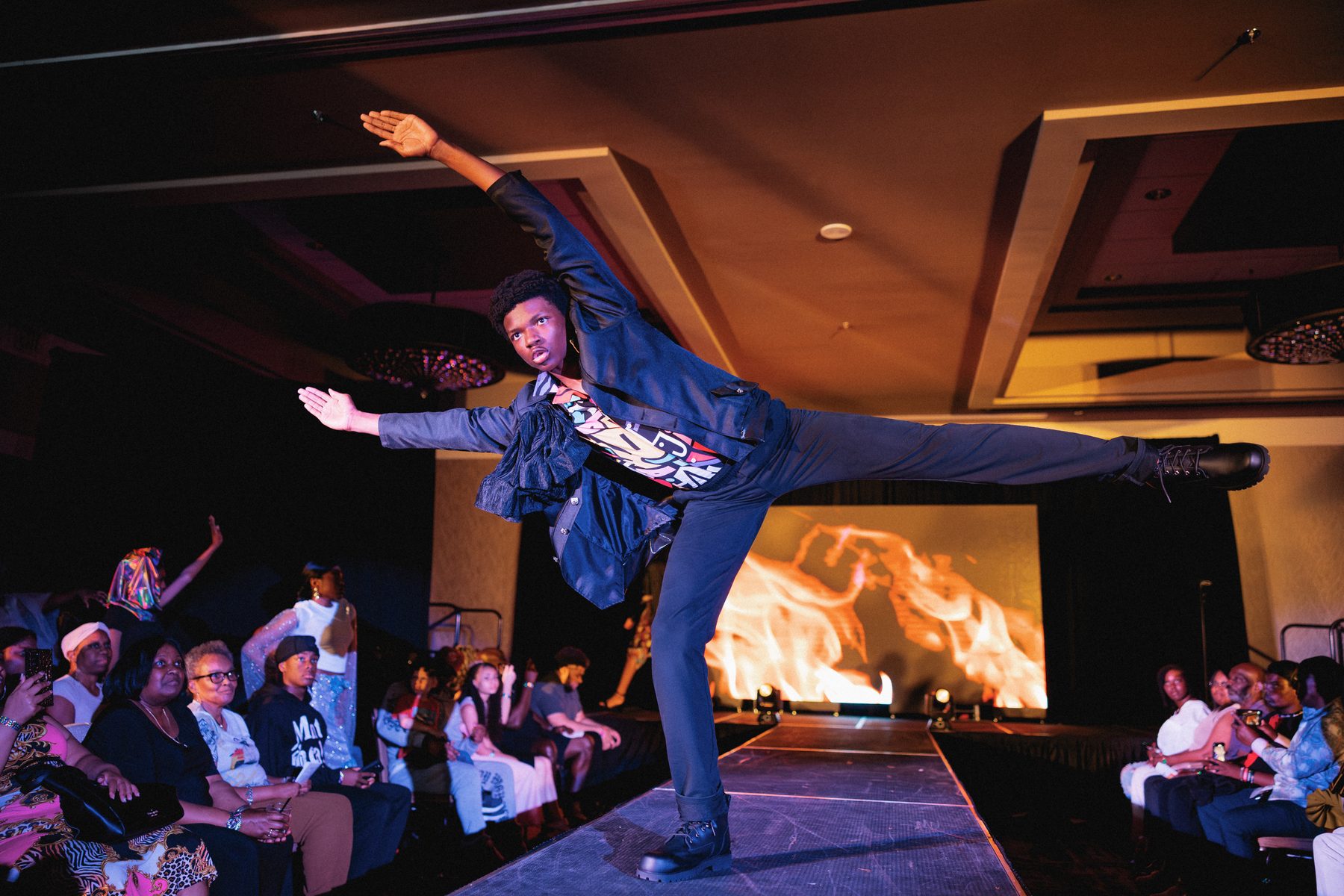 A young man holds a powerful dance pose on the runway.