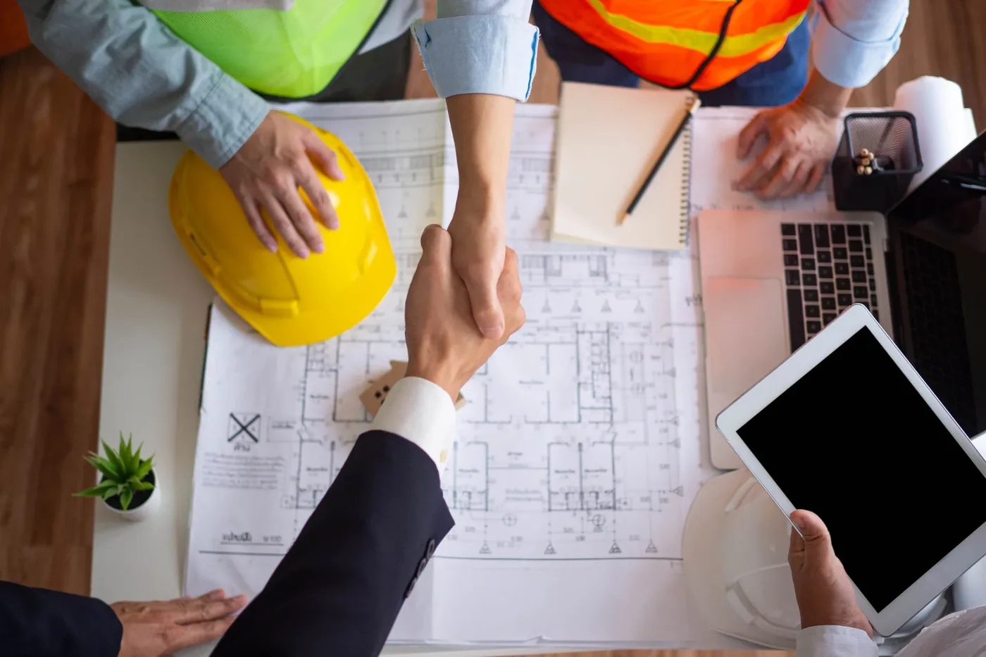 Cliente y contratista cerrando un trato sobre planos de construcción
