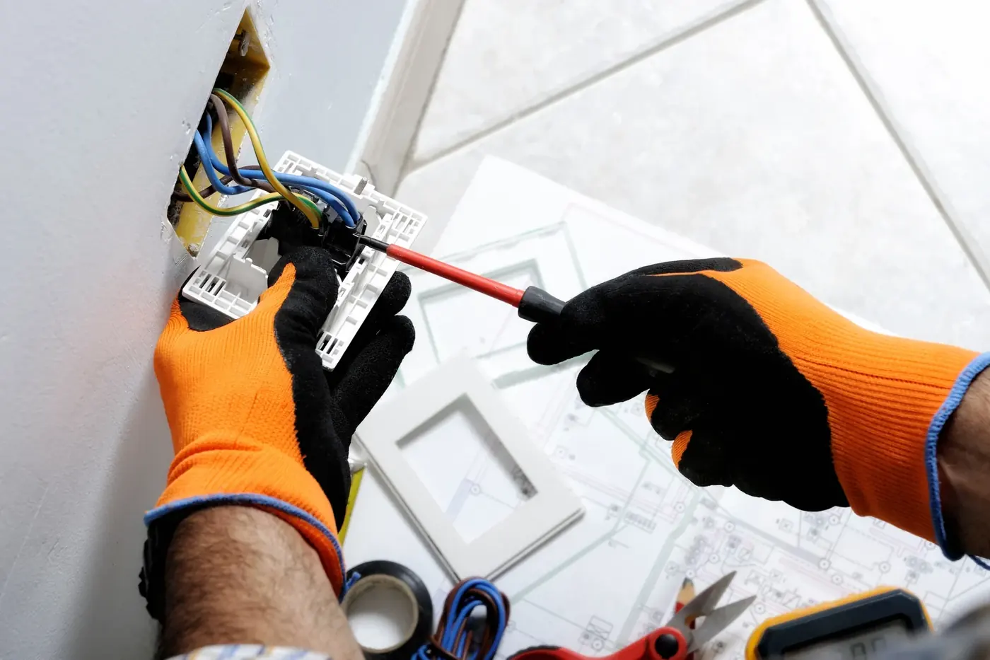 Electricista instalando cableado sobre planos