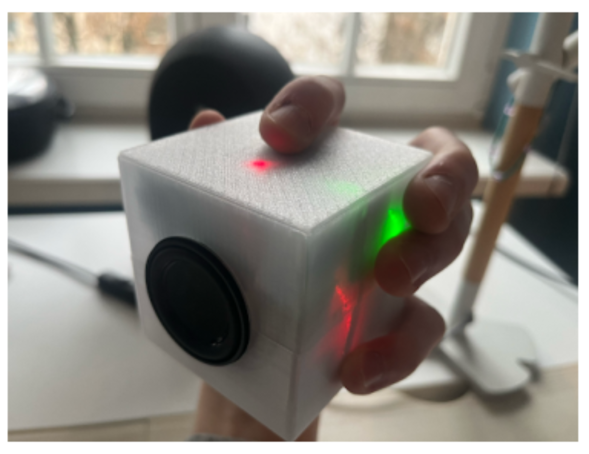 原论文 Figure 1:SonoCube held in hand, showing the 70mm translucent PETG enclosure and touch sensor LED indica- tor.