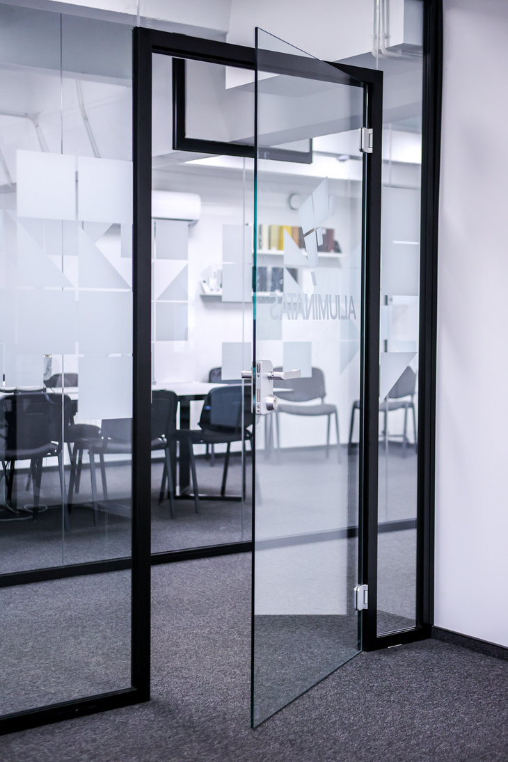 Frameless glass door leaf in a glazed office partition