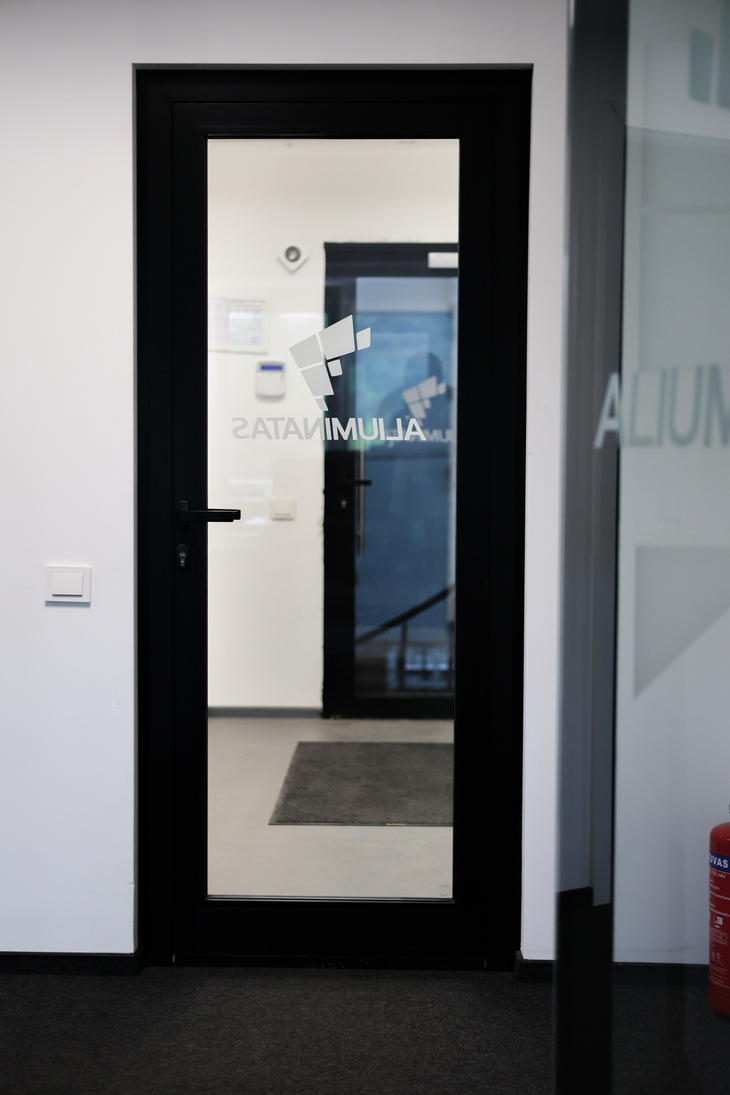 Solid timber-faced door leaf set into an aluminium glazed partition frame