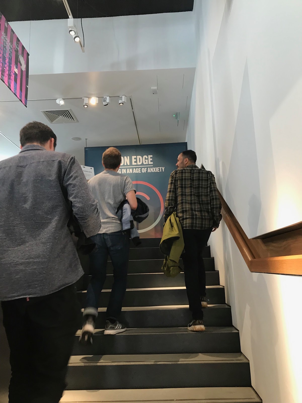 Three team members walking up stairs to exhibit with backs turned