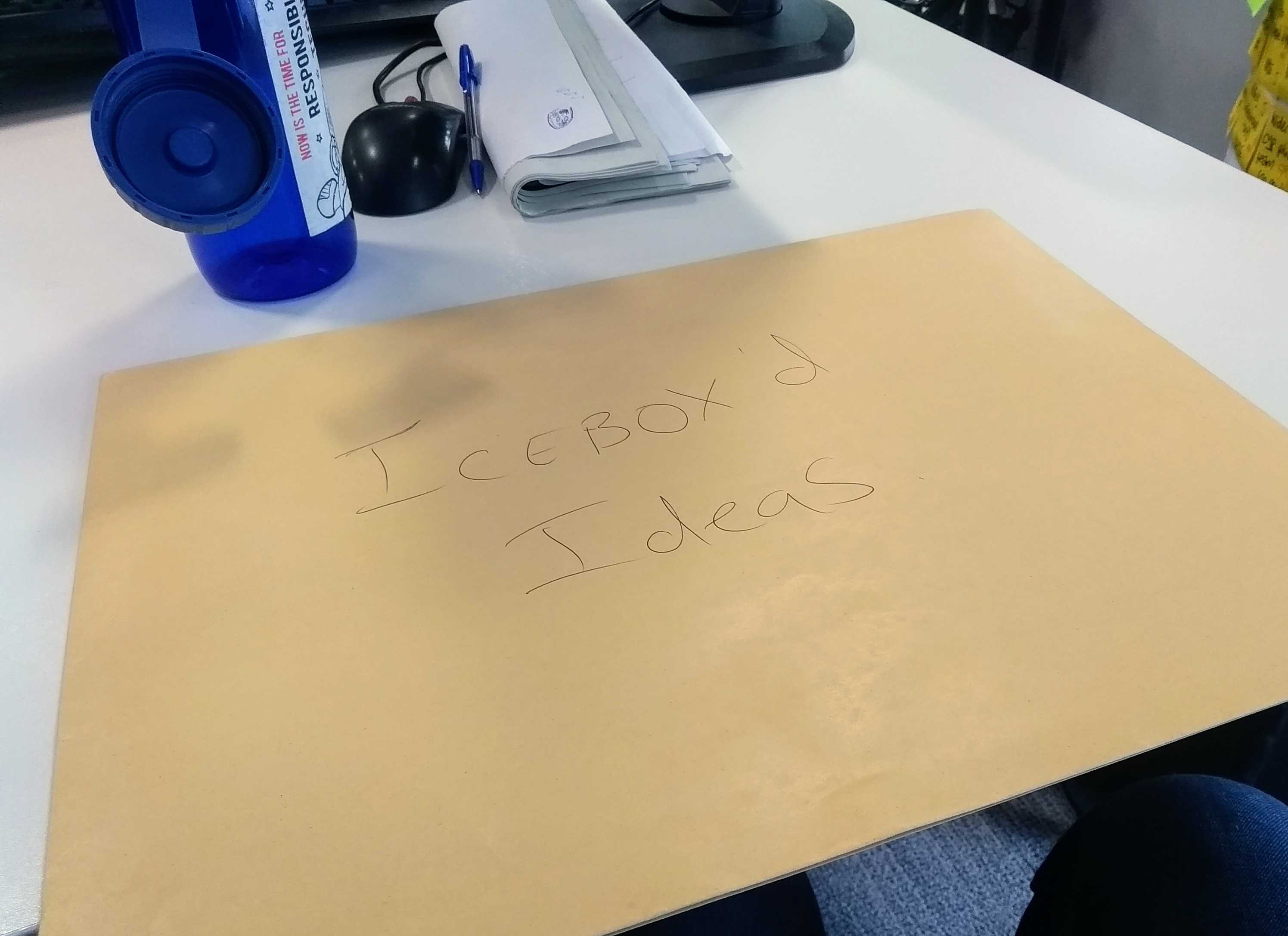 A envelope with text on it saying “icebox’d ideas” on a desk next to a water bottle