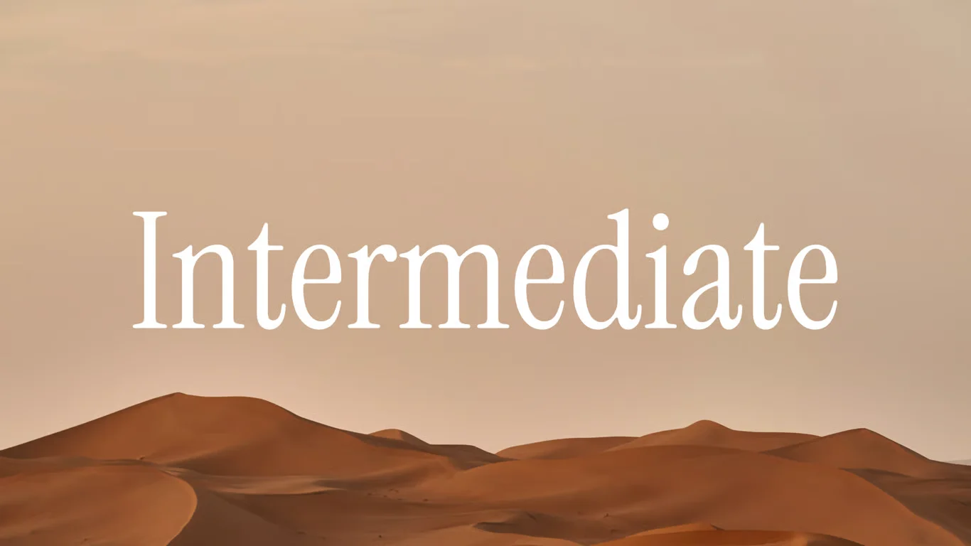 A hazy orange sky over a shadowed dark brown sand dune.