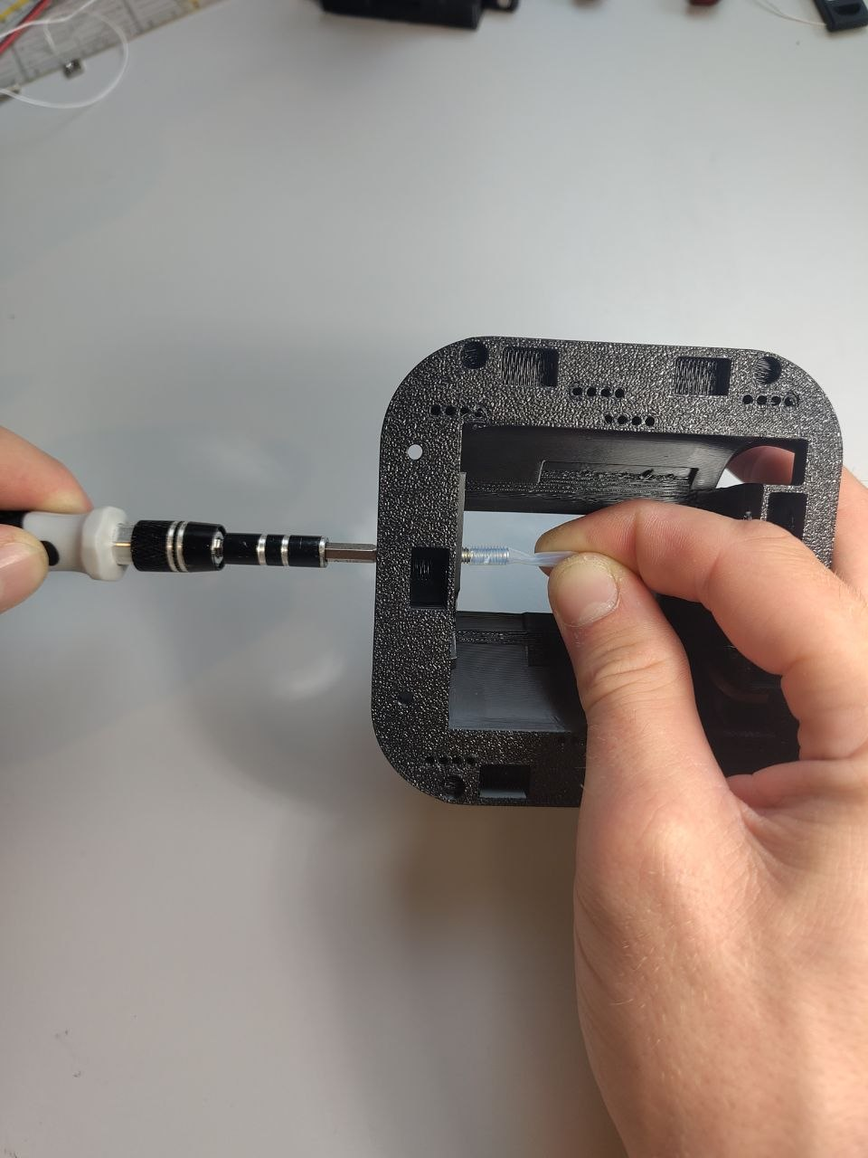Using a screwdriver to drive an M4 screw into the PTFE tube