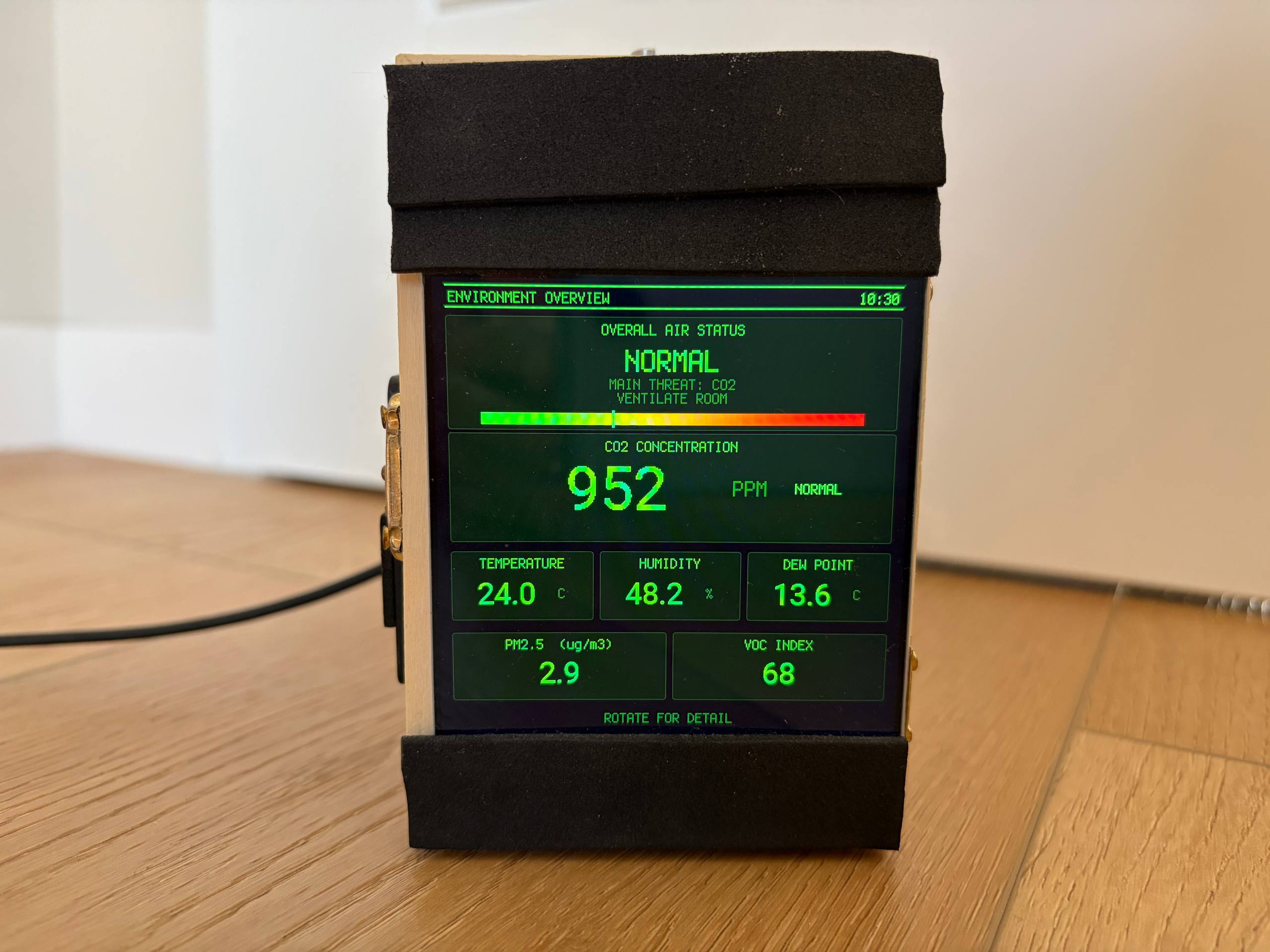 Small wooden box with a square screen showing green Pip-Boy style text: air status NORMAL, CO2 952 ppm, temperature 24.0 C, humidity 48.2 percent.